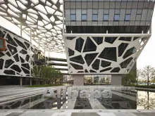 Photograph of Alibaba headquarters in Hangzhou, showing the Alibaba name in stone reflected in a plaza pool in front of the building.