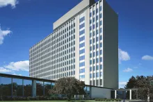 Photograph of the tall NIST administration building in Gaithersburg under a blue sky.