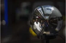 A photograph of a reflective World Orb verification device reflecting people standing in front of it.