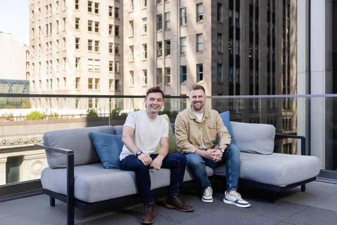 Photograph of General Compute founders Finn Puklowski and Jason Goodison seated on a rooftop terrace.