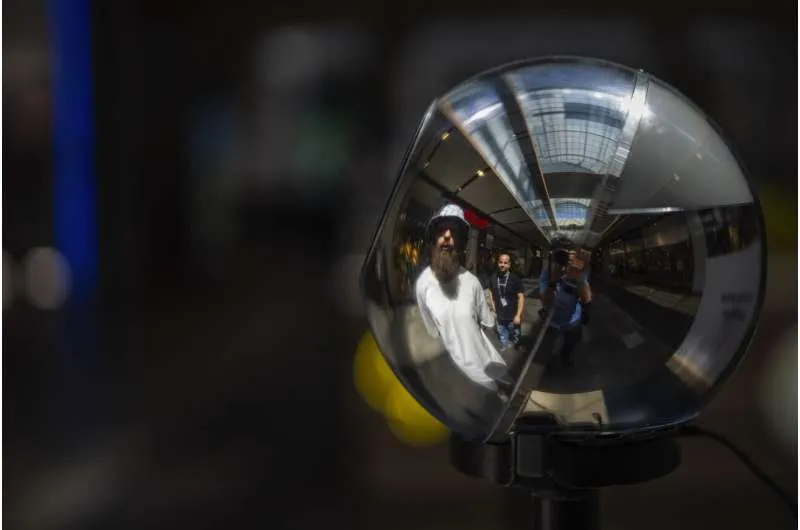 A photograph of a reflective World Orb verification device reflecting people standing in front of it.